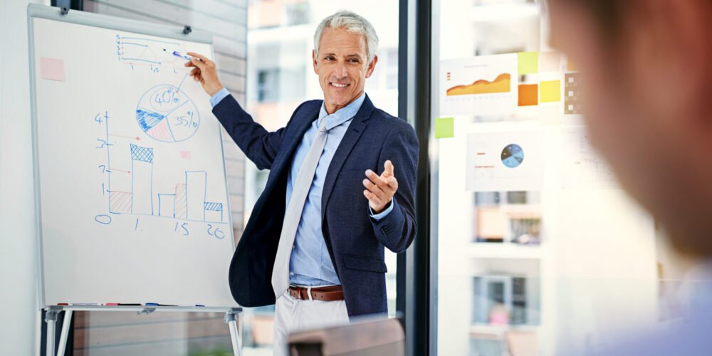 Senior Reltic construction consultant presenting project cost timeline and risk position to developers in a UK office